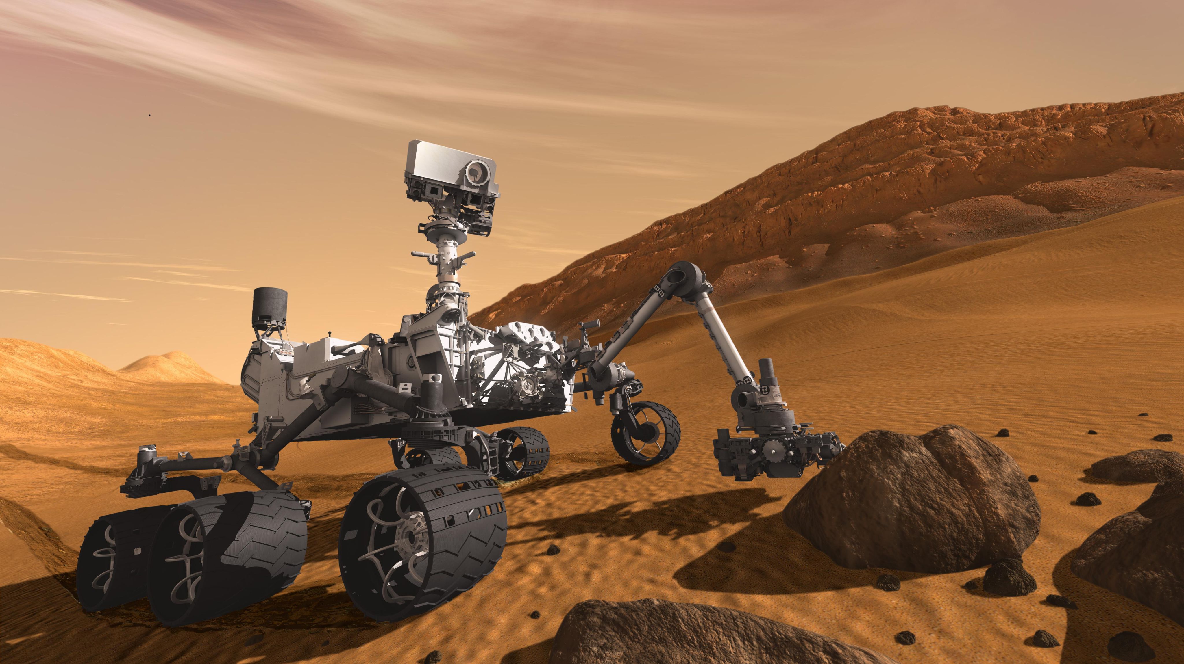 The four-legged Curiosity Rover inspects rocks on the surface of Mars.